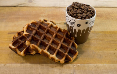 Two fresh waffles with cup full of coffee beans