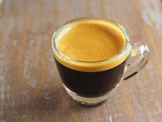Cup of hot espresso coffee on wood table, background