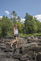 Naklejka premium attractive young woman kneeling by a river bank and smiling at t