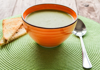 Pea soup in an orange plate with crackers