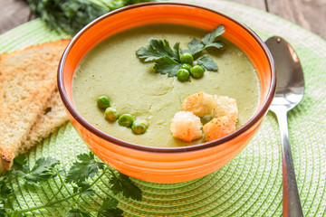 Pea soup in an orange plate with crackers