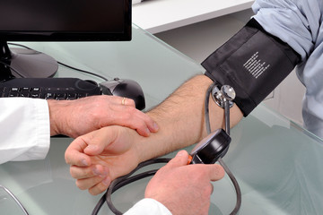 Doctor in his consulting room measures the blood pressure of a patient