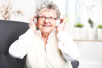 Babcia słucha muzyki. Starsza kobieta z słuchawkami na uszach słucha muzyki - obrazy, fototapety, plakaty