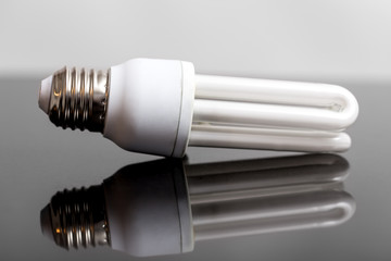 Energiesparlampe auf grauem Glas mit Spiegelung