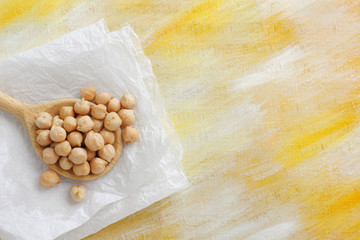 Still life with chickpea seeds on wooden spoon and paper cloth