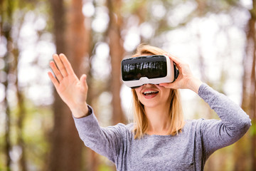 Woman wearing virtual reality goggles outside in spring nature