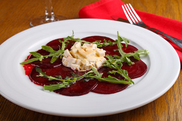 beet salad and cheese and arugula in a white plate