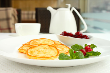 sweet pancakes with cherry sauce decorated with mint and raspberries