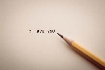 word "I LOVE YOU" on notebook with pencil