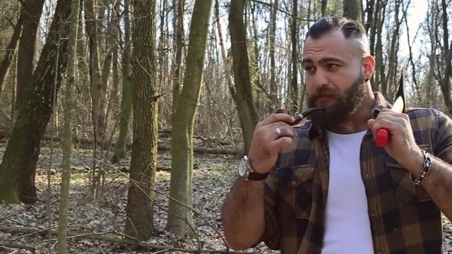 bearded lumberjack smoking a pipe in the woods
