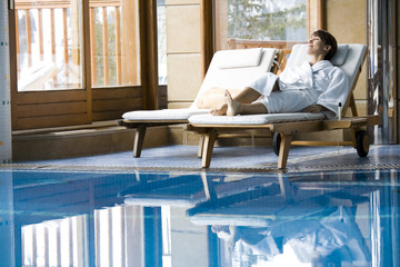 femme couchée sur un transat au bord d'une piscine intérieure