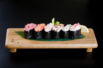 Japanes food. Assorted Sushi gunkan on a wooden plate on black b