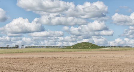 Fototapeta na wymiar A Bronze Age burial mound in open farmland.