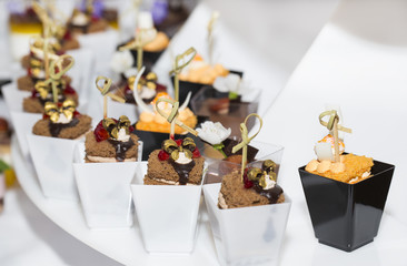 mini canapes in plastic cups decorated with edible flowers