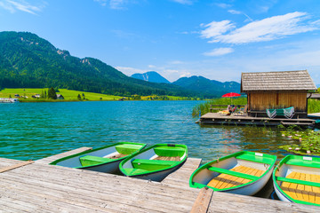 Tourist boats on shore of Weissensee lake in summer landscape of Alps Mountains, Austria