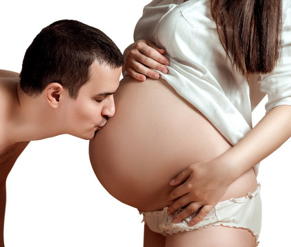 Husband kisses the tummy of his pregnant wife. Listening to the unborn baby. Isolated image on the white background.