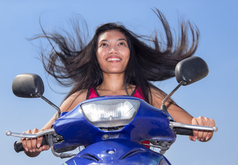 Fototapeta na wymiar woman with flying hair riding a motorbike on a blue background