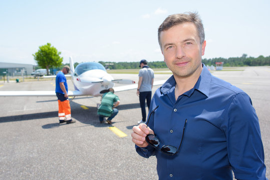 Portrait of man on runway with light aircraft
