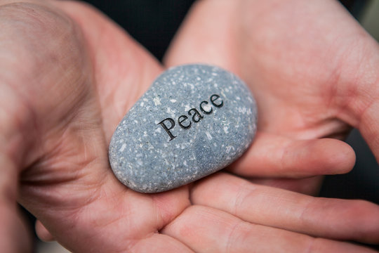 Inner balance concept: hands holding stones with the word peace 