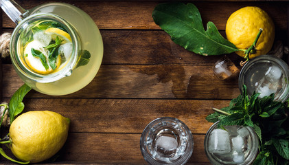 Homemade mint lemonade served with fresh lemons and ice over wooden background, top view, copy space - obrazy, fototapety, plakaty