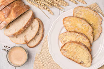 Fresh bread, homemade butter and coffee on wooden background.