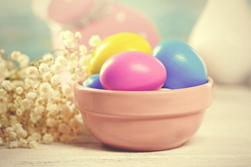 Colorful Easter eggs in bowl on wooden table, closeup . Retro stylization