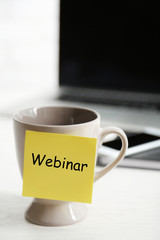 A cup with sticky note on the office table, close up. Webinar concept
