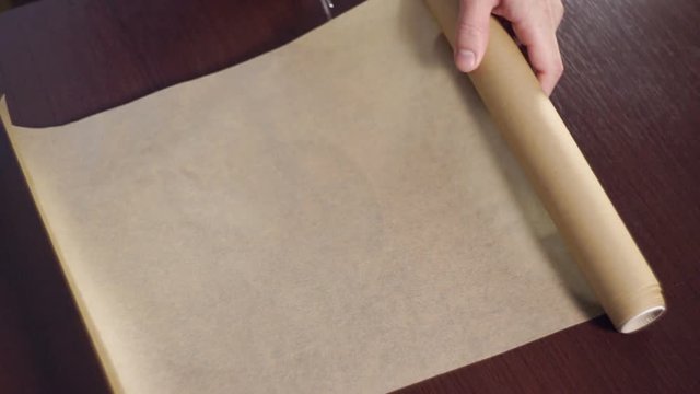 Cook cutting a section of greaseproof paper with scissors. Cutting baking paper and coating round baking pan. Kitchen utensils. Baking paper. Non-stick paper for baking