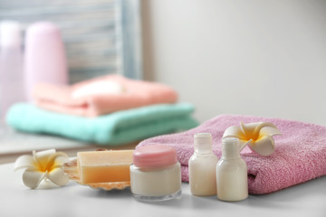 Fototapeta na wymiar Blue towel with cosmetics and soap on bathroom table