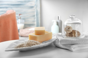 Fototapeta na wymiar Soap with salt, towels and shells on bathroom table