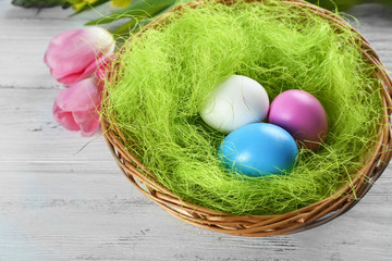 Easter eggs in nest with spring flowers on white wooden table