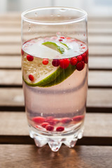 drink from cowberry and a lime in a glass on a table, selective focus