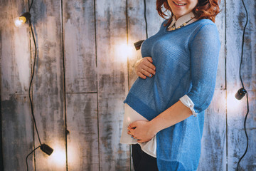 Young woman pregnant in blue outfit. Red hair. Smiling happily