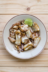 Grilled squids with lemon on wooden board