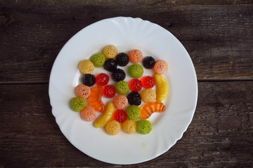 Fruit jelly in the form of berries and fruit on a plate on a woo