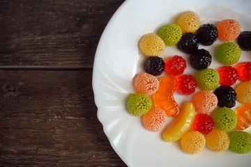 Fruit jelly in the form of berries and fruit on a plate on a woo