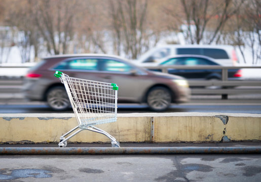 shopping cart on background rushing cars