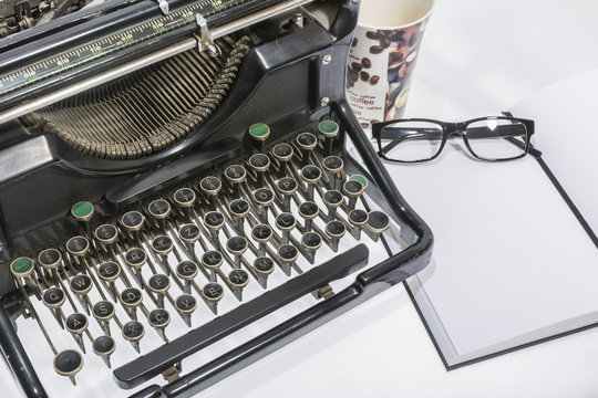 antique typewriter with coffe, a blank and a pencil on white background