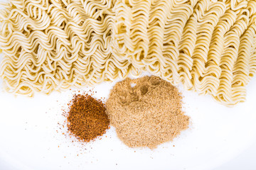 Unhealthy flavoring powder with uncooked instant noodles in backkground isolated in white 