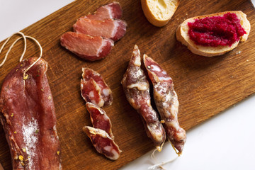 Top view horizontal image of various meats on serving board. Ham, pork, beef and homemade bread with beetroot-horseradish spread.
