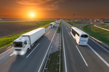 White truck and bus in motion blur on the highway at sunset