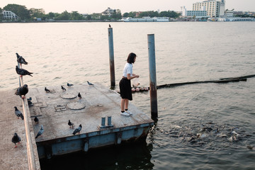 woman student feeding fish at port