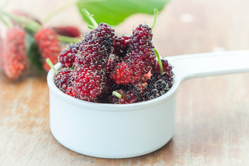 Mulberry in bowl on wooden background. Selective