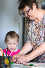 Woman helping girl mold from plasticine. Girl sits at the table