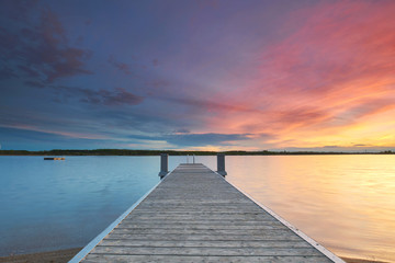 Obraz na płótnie Canvas pastellfarbener Sonnenuntergang am Meer mit Holzsteg