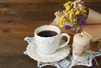 bright and colorful dried flowers on the books around a little candle and a Cup of strong black coffee on wooden background