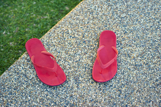 pair of red comfortable slipper placed of stony floor