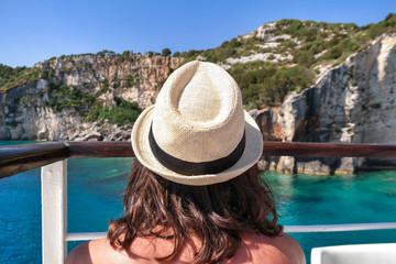 Rear view of young woman enjoying warm sunny day on the cruise. Blue caves in Zakynthos Island
