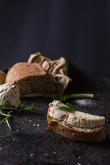 Black food background with homemade bread loaf and  fresh aromatic ruccola , copy space. Top view