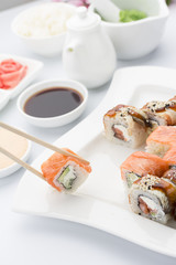 Salmon sushi roll in chopsticks